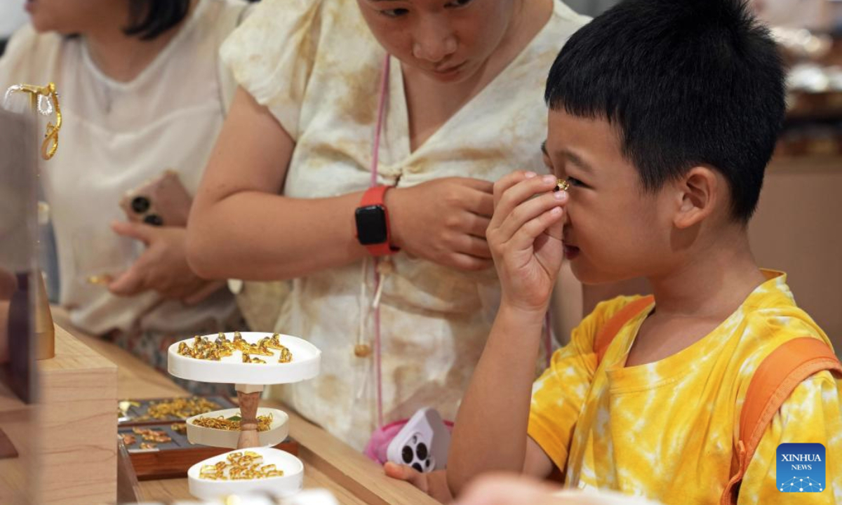A child selects goods at a cultural and creative product shop at the Shanghai Museum at night in Shanghai, east China, Aug. 11, 2025. The exhibition, titled On Top of the Pyramid: The Civilization of Ancient Egypt, opens 24 hours a day from Aug. 11 to 17 at the Shanghai Museum. During the 168-hour carnival, there will also be new books releases, Egyptian dancing performances, interactive games and cultural and creative production promotions here. (Xinhua/Liu Ying)